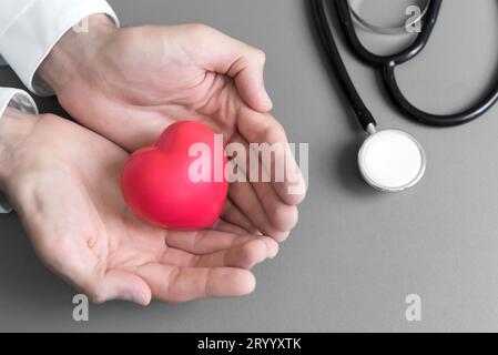 Mani del medico che tengono e danno il cuore di massaggio rosso al paziente per guarire dalla malattia. Concetto ospedaliero e sanitario. CPR e c Foto Stock