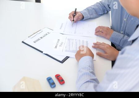 Responsabile delle vendite che dà il documento di modulo di richiesta di consiglio, considerando l'offerta di prestito ipotecario per l'assicurazione dell'automobile e della casa. Foto Stock