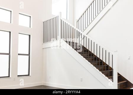 Moderna scala in legno bianco negli interni di una nuova casa con grandi finestre Foto Stock