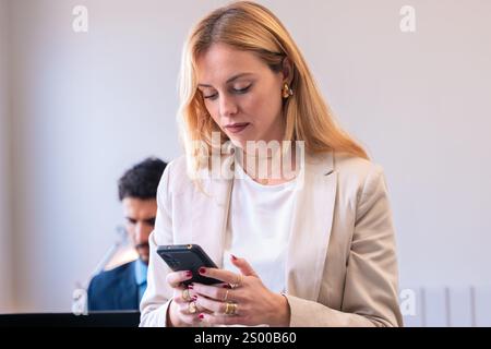 Donna d'affari che controlla lo smartphone in ufficio Foto Stock