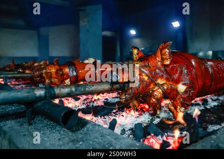 Metro Manila, Metro Manila, Filippine. 23 dicembre 2024. I lechon (Whole Roasted Pigs) vengono cucinati su carbone all'interno di una mini fabbrica dove le temperature possono raggiungere i 65 gradi Celsius, mentre i filippini si preparano per il Natale con la cucina iconica, a Metro Manila, nelle Filippine, il 23 dicembre 2024. Il lechon è stato a lungo parte delle importanti culture alimentari delle Filippine fin dall'era coloniale spagnola. Fiore all'occhiello delle celebrazioni filippine, soprattutto per il periodo natalizio, Lechon è un maiale tostato che richiama l'attenzione sul tavolo da pranzo, come la sua pelle croccante Foto Stock