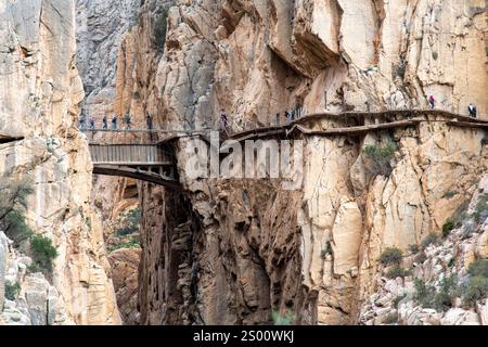 Persone che camminano sul sentiero El Caminito del Rey (il piccolo sentiero del re) vicino a El Chorro, Malaga, Spagna, fissato lungo le ripide pareti di un nar Foto Stock