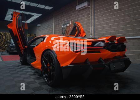 Lamborghini Revuelto arancione con porte a forbice in ambiente interno Foto Stock