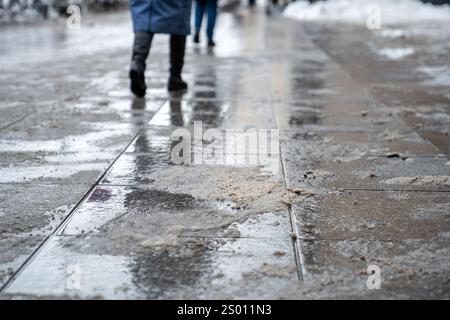 Prodotti chimici antigelo. Donna che cammina per strada trattata con sale tecnico o prodotti chimici antighiaccio Foto Stock