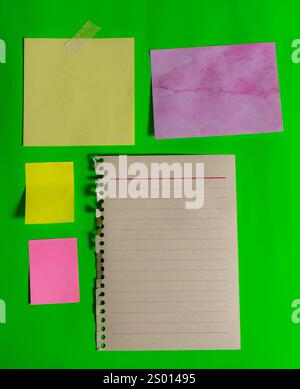 Carta bianca diversa di dimensioni, colori e forme diverse su una superficie verde. Orientamento verticale Foto Stock