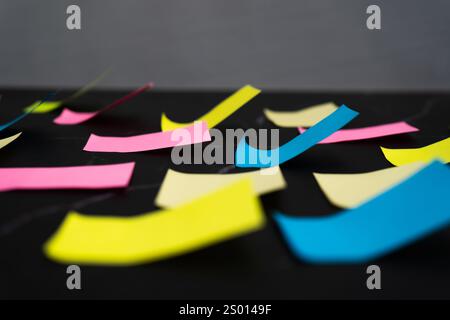 Note adesive colorate disposte su una superficie nera per un'organizzazione creativa delle idee. Vista normale. Foto Stock