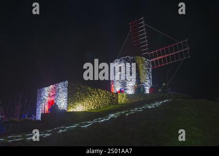 Storico mulino a vento di notte, illuminato con luci moderne rosse e blu, su una collina, mondo di luci, illuminazione, museo del mulino, Gifhorn, bassa Sassonia Foto Stock