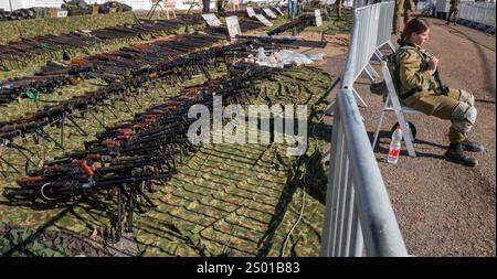 Amirim, Israele. 23 dicembre 2024. Un soldato israeliano siede di guardia fuori da una mostra di centinaia di fucili d'assalto leggeri e RPG (Rocket Propelled Granades) sequestrati alle forze di Hezbollah in mostra in una base dell'esercito israeliano non lontano dal confine con il Libano meridionale il 23 dicembre 2024. L'IDF mise in mostra circa 86.000 oggetti che hanno catturato nel sud del Libano, a sud del fiume Litani, durante i combattimenti contro le forze di Hezbollah che iniziarono Octobert 1, 2024. Foto di Jim Hollander/UPI credito: UPI/Alamy Live News Foto Stock