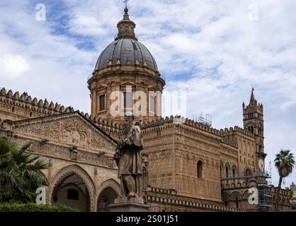 Un edificio storico con una grande cupola e intricati dettagli architettonici, circondato da palme e una statua in primo piano. Il cielo è in parte Foto Stock