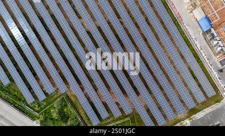 Vasti pannelli solari si estendono attraverso il paesaggio, riflettendo la luce del sole mentre generano energia rinnovabile. Le righe di pannelli creano un motivo geometrico, surr Foto Stock