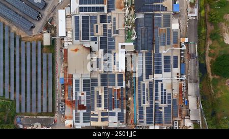 Questa vista aerea mostra estese installazioni di pannelli solari sui tetti di edifici commerciali in un'area industriale. Foto Stock
