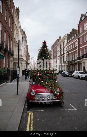 Mini auto decorata con decorazioni natalizie parcheggiata in una strada laterale di Mayfair nel quartiere più ricco di Londra, Inghilterra, Regno Unito Foto Stock