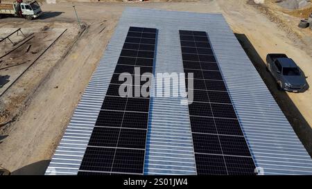 Le soluzioni energetiche sostenibili vengono implementate con pannelli solari installati di recente sul tetto di un edificio. Il cantiere risulta in corso Foto Stock