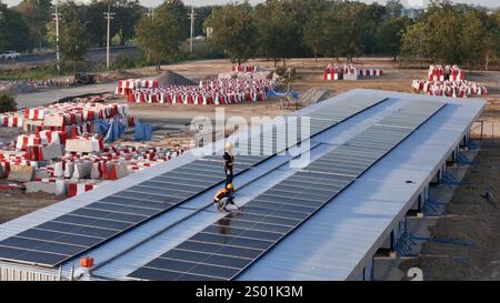 I lavoratori stanno installando pannelli solari sul tetto di un edificio commerciale in costruzione. Intorno al sito si trovano i materiali da costruzione e il barri Foto Stock