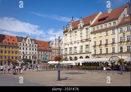 I visitatori si riuniscono nella vivace Piazza del mercato, godendosi il sole e l'affascinante architettura di Breslavia, Polonia Foto Stock