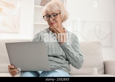 Bella donna anziana che usa il laptop a casa Foto Stock