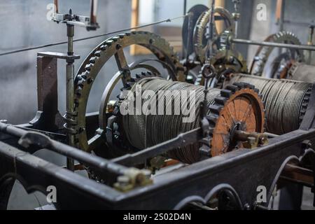 Primo piano di una vecchia macchina industriale con ingranaggi e cavi, che mostra dettagli meccanici complessi e ingegneria vintage, ideale per applicazioni industriali Foto Stock