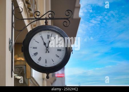 Un bellissimo orologio da parete classico sullo sfondo del sereno cielo blu Foto Stock