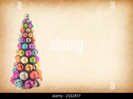 Palline colorate di Natale sovrapposte a forma di albero di natale su carta spaccata antica Foto Stock