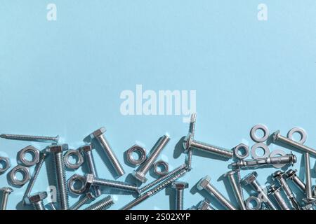 Diversi bulloni filettati e dadi cromati su sfondo blu Foto Stock