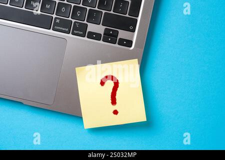 Un punto interrogativo è stato scritto su un foglio adesivo attaccato all'angolo del notebook Foto Stock