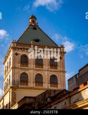 Un edificio storico con un distintivo tetto piastrellato verde e dettagli architettonici ornati. La struttura presenta finestre ad arco multiple e decorazioni Foto Stock