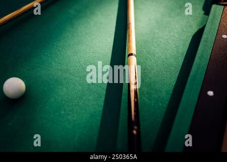 Un tavolo da biliardo con palle da biliardo sparse, un bastoncino e accessori catturati in una scena dinamica e pronta per il gioco. L'attenzione dettagliata sull'apparecchiatura Foto Stock