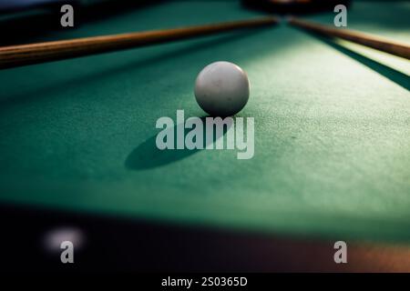 Un tavolo da biliardo con palle da biliardo sparse, un bastoncino e accessori catturati in una scena dinamica e pronta per il gioco. L'attenzione dettagliata sull'apparecchiatura Foto Stock