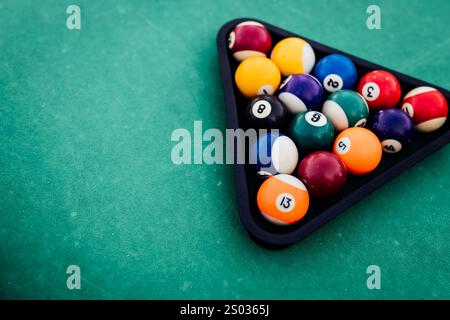 Un tavolo da biliardo con palle da biliardo sparse, un bastoncino e accessori catturati in una scena dinamica e pronta per il gioco. L'attenzione dettagliata sull'apparecchiatura Foto Stock