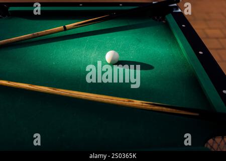 Un tavolo da biliardo con palle da biliardo sparse, un bastoncino e accessori catturati in una scena dinamica e pronta per il gioco. L'attenzione dettagliata sull'apparecchiatura Foto Stock