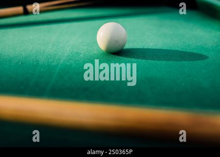 Un tavolo da biliardo con palle da biliardo sparse, un bastoncino e accessori catturati in una scena dinamica e pronta per il gioco. L'attenzione dettagliata sull'apparecchiatura Foto Stock