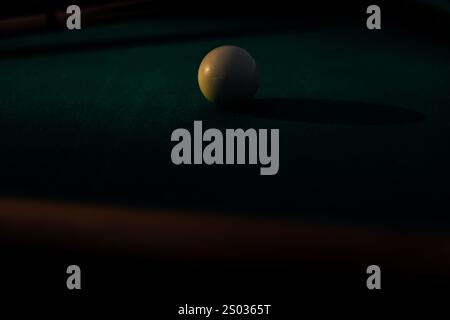 Un tavolo da biliardo con palle da biliardo sparse, un bastoncino e accessori catturati in una scena dinamica e pronta per il gioco. L'attenzione dettagliata sull'apparecchiatura Foto Stock