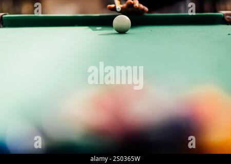Un tavolo da biliardo con palle da biliardo sparse, un bastoncino e accessori catturati in una scena dinamica e pronta per il gioco. L'attenzione dettagliata sull'apparecchiatura Foto Stock