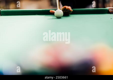 Un tavolo da biliardo con palle da biliardo sparse, un bastoncino e accessori catturati in una scena dinamica e pronta per il gioco. L'attenzione dettagliata sull'apparecchiatura Foto Stock