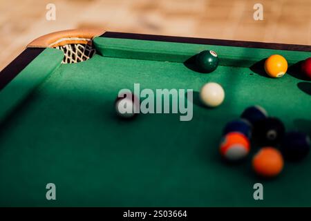 Un tavolo da biliardo con palle da biliardo sparse, un bastoncino e accessori catturati in una scena dinamica e pronta per il gioco. L'attenzione dettagliata sull'apparecchiatura Foto Stock