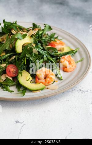 Primo piano di un'insalata di gamberi con verdure fresche, pomodori ciliegini, avocado e scaglie di mandorle. Foto Stock