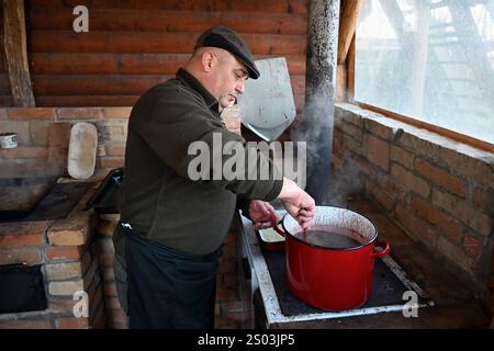 Ohrady, Dunajská Streda, Slovacchia - novembre 30 2024: Massacro di maiale della comunità tradizionale del villaggio (zabíjačka), uomo che cucina il sangue di maiale Foto Stock