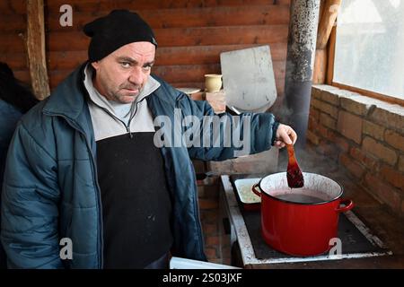 Ohrady, Dunajská Streda, Slovacchia - novembre 30 2024: Massacro di maiale della comunità tradizionale del villaggio (zabíjačka), uomo che cucina il sangue di maiale Foto Stock