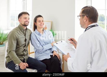 Dottore consulenza coppia positiva sulla pianificazione della gravidanza in ospedale Foto Stock