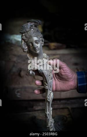 Un dettaglio di artigianato in bronzo, sapientemente fatto a mano in un laboratorio di strada di Alessandria, Egitto. La mano dell'artigiano mette in risalto l'intricata maestria artigianale. Foto Stock