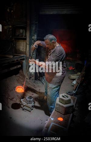 Lavoratore di fonderia in un'officina ad Alessandria, Egitto, che maneggia sapientemente il metallo fuso durante un processo di fusione. Un'immagine del fondatore di Brass Foto Stock
