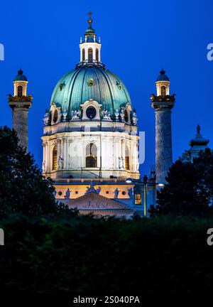 Una splendida vista di una storica struttura a cupola illuminata di notte, circondata da alberi e caratterizzata da colonne ornate. Il cielo è un blu profondo, che si esalta Foto Stock