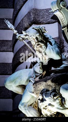 Primo piano di una scultura drammatica raffigurante una figura muscolare con una barba, tenendo in mano un tridente, seduta su una roccia. La figura è dettagliata, Foto Stock