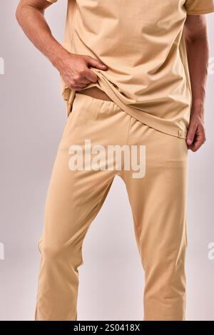 Outfit casual beige caratterizzato da una mano che regola la texture del tessuto confortevole, ideale per un concetto di abbigliamento rilassato Foto Stock