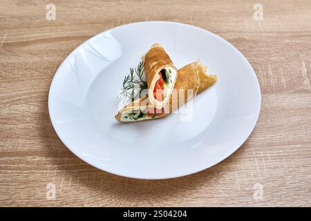 Pancake sottili ripieni di salmone affumicato, formaggio spalmabile e aneto fresco. Foto Stock