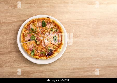 Pizza condita con pancetta, sottaceti, cipolle rosse ed erbe fresche, tagliata a fette. Foto Stock