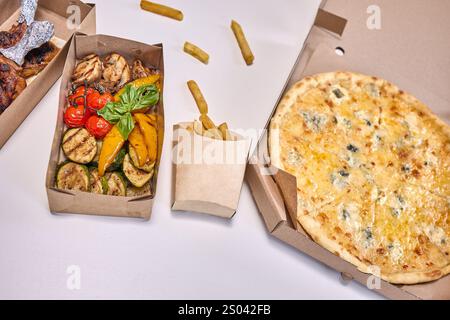 Un piatto piatto di piatti fast food popolari come hamburger, pizza e pollo, pronti per la consegna. Foto Stock