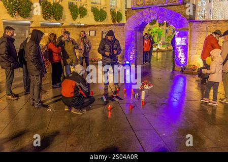 Logrono, la Rioja, Spagna. 24 dicembre 2024. Un gruppo di attivisti filo-palestinesi ha fatto un intervento pacifico nella città di Betlemme di Logroño, collocando candele, fiori e manifesti con i nomi dei bambini uccisi nel conflitto di Gaza. L'azione simbolica cerca di rendere visibile l'impatto umanitario del conflitto durante le festività natalizie, utilizzando il simbolismo della nascita di Gesù a Betlemme per sensibilizzare sulla situazione attuale in Palestina. I manifestanti hanno accuratamente disposto le candele formando un percorso verso il presepe, mentre i nomi delle vittime minori sono d Foto Stock