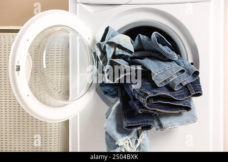 Lavatrice con jeans sporchi e altri indumenti in denim all'interno Foto Stock