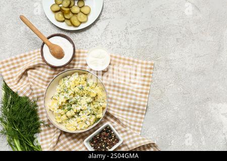 Ciotola di gustosa insalata di patate con aneto, grani di pepe, sale, panna acida e fette di cetriolo sottaceto su fondo grunge grigio Foto Stock